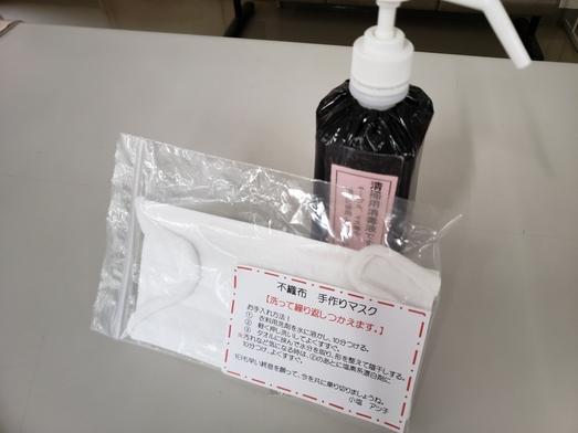 黒いボトルに入った消毒液と透明な袋に手作りマスクとお手入れ方法のメモが入っている写真