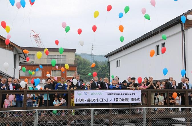 玖珠・森のクレヨン、森の米蔵開所式で参加者達が色とりどりの風船を空に放っている写真