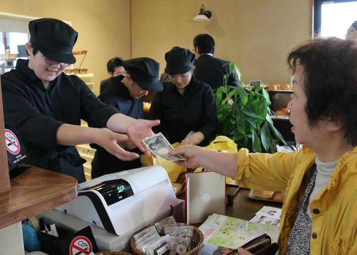 女性がレジで店員に支払いをしている写真