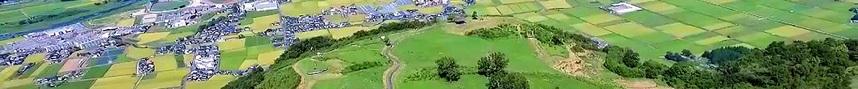 玖珠町を山の上から見下ろして、左側に町が小さく見え、右側には田んぼが広がっている様子の写真