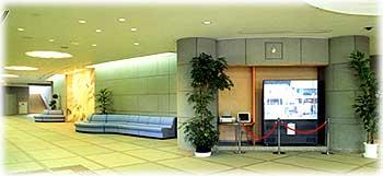 メルサンホール入口を入った正面には大きなディスプレイや植木があり、横には青い長いソファーやオレンジ色に光る四角いオブジェがある広い玄関ホールの写真