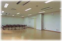 がらんとした広い部屋の奥に机と椅子が複数置かれている学習室の写真