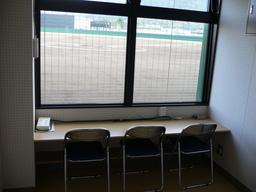 2つの窓側に机と3つのパイプ椅子が設置されている放送室の写真