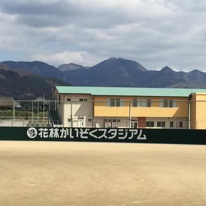 野球場の外野ラバーフェンスにロゴマークと白字で「花林かいぞくスタジアム」と書かれた写真