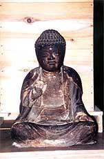 眼光鋭く右手が上がり、左手を膝の上に乗せて座っている、木彫りの天承庵本尊仏の写真