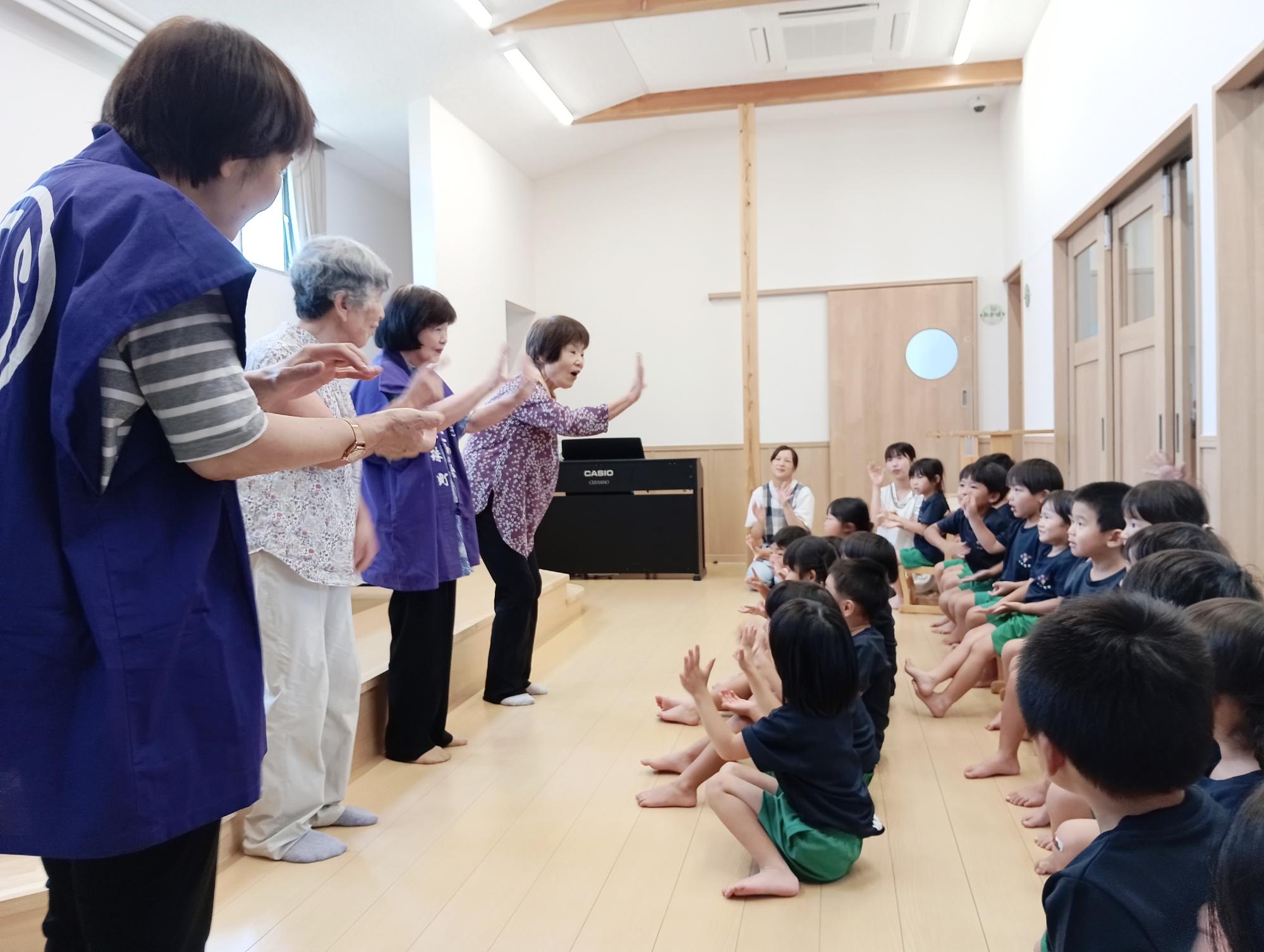 ひこわの会のみなさんが園児と手遊びをしている写真