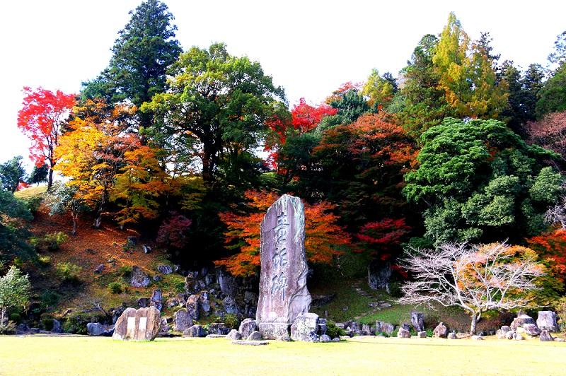 旧久留島氏庭園にある大きな石碑と、大きな木々が並んでいる写真