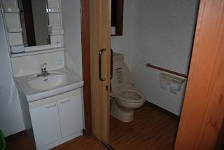 白い洗面台と、入口のドアが引き戸になっている洋式トイレが写っている写真